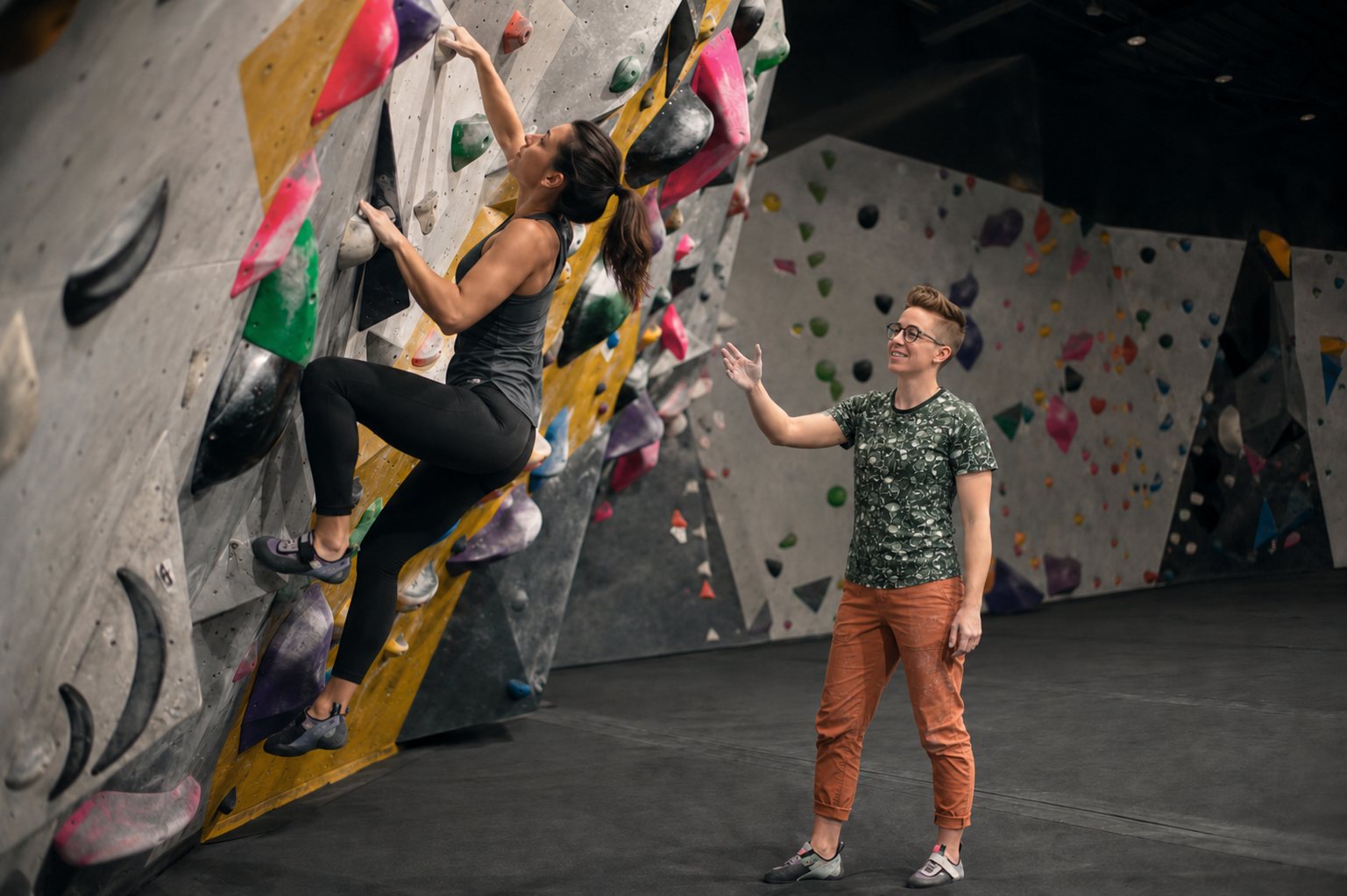 Sara coaching a climber through a move on a bouldering wall